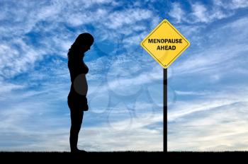 Sad woman standing at the road sign menopause ahead. Conceptual image of impending menopause in women