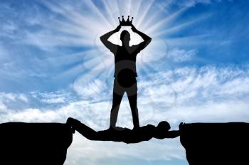 Selfish man puts his crown on his head, he is on the man in the form of a bridge over the abyss. Concept of selfishness in relationships between people