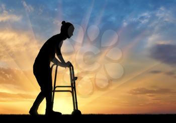 Silhouette of a disabled woman walking, using a walker for the disabled. The concept of the elderly and disabled