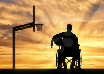 Silhouette of a disabled basketball player in a wheelchair holding the ball in his hand. The concept of disabled people leading an active lifestyle