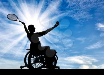 Silhouette of disabled person in a wheelchair playing tennis. The concept of disabled people leading an active lifestyle