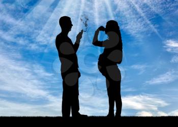 Silhouette of a man egoist smoking near a pregnant woman. She covered her nose with her hand from the smoke. The concept of a selfish person who thinks only of himself