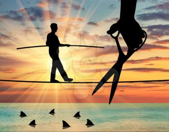 Silhouette of a businessman walking on a rope balancing, under it sharks, a hand with scissors intends to cut the rope. Concept of risks and dangers in business