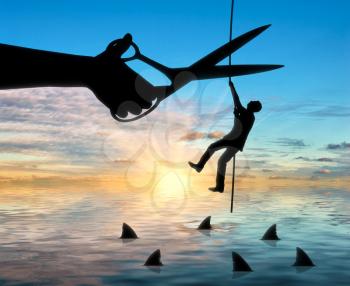 Silhouette of a businessman climbs a rope above the sharks and a hand with scissors intends to cut the rope. The concept of competition and risks in business