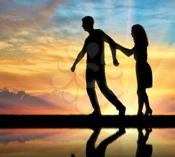 The concept of divorce and parting of a married couple. Silhouette of man throwing woman on sunset background