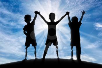 Children's disability concept. Children with disabilities with a prosthetic leg standing, holding hands against sky