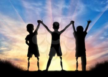 Children's disability concept. Happy children with disabilities with a prosthetic leg standing, holding hands on sunset background