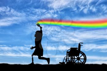 Children's disability concept. The child has a disability with a prosthetic leg with a brush in hand, runs, and draws a rainbow in the sky and next to wheelchair