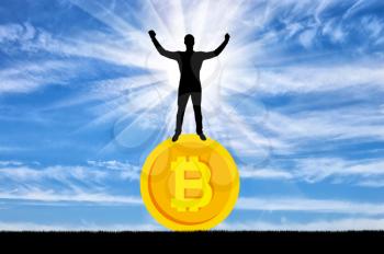 Happy man standing on a coin bitcoin. The concept of success in the crypto currency