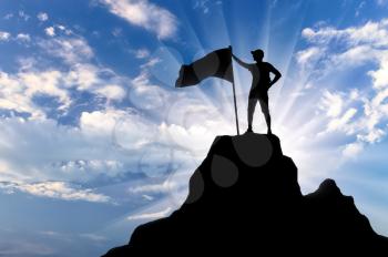 Silhouette of a climber with a flag on top of a mountain. Conceptual scene of success
