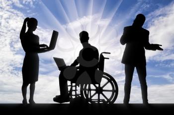 Disabled working concept. Silhouette of a man disabled worker in a wheelchair with a laptop and his work team
