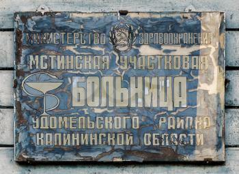 Village Gorodishche, Russia - 22 May 2014: The old cracked discolored sign rural hospitals. Inscription in Cyrillic.