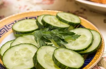 Slices of fresh cucumber. Focus on a leaf of parsley.