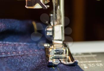 Sewing machine and jeans fabric. Focus on the needle.