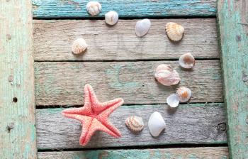 Red starfish and seashells on a wooden background.
