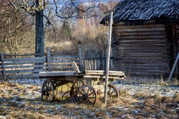 An old wooden cart stands on snow-covered grass.