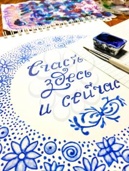 Watercolor doodle. A ribbon of blue flowers, spirals and dots. The inscription in Russian language: happiness is here and now. Mobile photo.