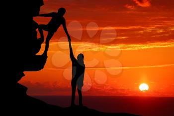 Teamwork couple hiking help each other trust assistance silhouette in mountains, sunset. Teamwork of man and woman hiker helping each other on top of mountain climbing team