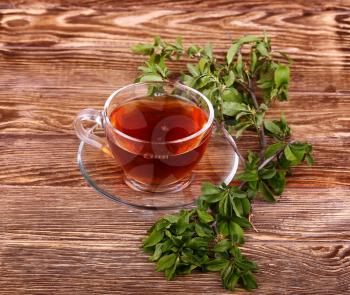 Glass cup of tea on a wooden table with  and mint leaves.