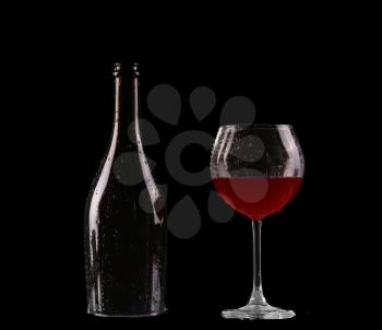 Elegant red wine glass and a wine bottle in black background