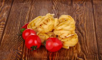 pasta on wooden background with tomato top view