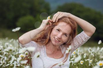 Young lovely smiling woman wonders on flower, tearing petals, close-up.