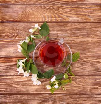 Herbal tea in a glass cup, fresh flowers on a background of wooden boards