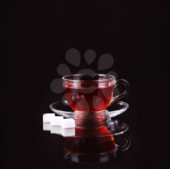 Glass cup of tea on black background.