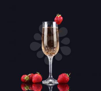 Glass of cold champagne with strawberries on a black background