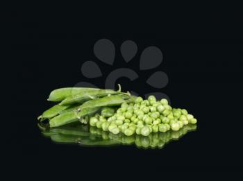 heaps of fresh crisp green peas in a pods on black background.