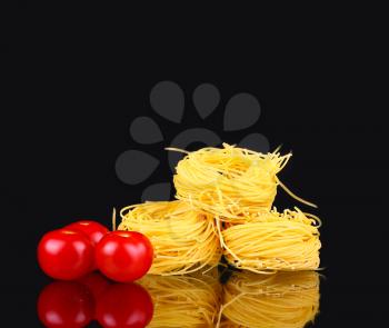 raw dry nest pasta with reflection on black with tomato