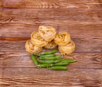 Pasta on the wooden background with peas