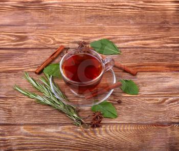 Glass cup of green tea with cinnamon sticks on a wooden table background.
