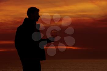 Silhouettes of man drinking a glass of champagne wine at sunset