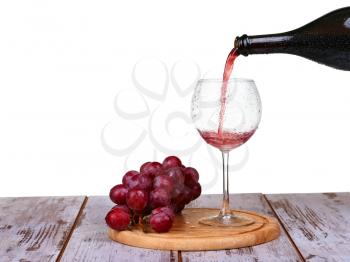 wine pouring into glass with grape and bottles isolated