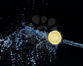 Half a lime falling into the water isolated on a black background