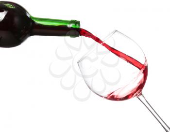 Red wine pouring from bottle into big glass on white background