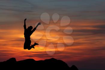 Happy woman jumping against beautiful sunset. Freedom, enjoyment concept.