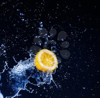 Lemon  into water splash on black background
