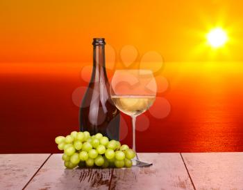 White wine grapes in a glass at sunset on a piece of wood