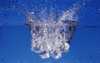 Ice cubes splashing into water, close-up
