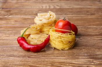 Pasta spaghetti noodles with chili pepper and tomatoes on wooden table