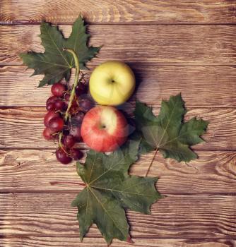 apples, grapes and leaves on wooden