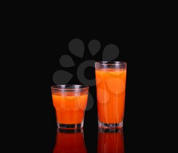 two glasses of grapefruit juice on black
