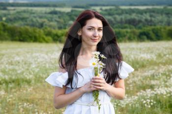 Beautiful woman on a flower granden enjoying her time outdoors. pretty girl relaxing outdoor, having fun, holding plant, happy young lady and spring green nature, harmony concept
