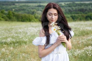 Beautiful woman on a flower granden enjoying her time outdoors. pretty girl relaxing outdoor, having fun, holding plant, happy young lady and spring green nature, harmony concept