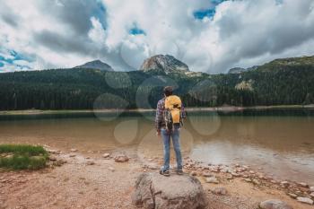Young man looking at Black Lake, Durmitor National Park, Zabljak, Montenegro. Hipster traveler enjoying view of Black Lake