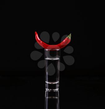Shot of vodka with chili peppers on a black background