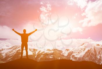 winner on a top of mountain. Meeting of the sun. The man on high mountain with the hands lifted above, on a background of a sunset