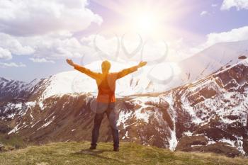 man hiker on a top of a mountain with raised hands and enjoying sunrise